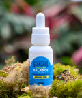 A 1 oz bottle of Appalachian Standard's Balance Extra Strength CBD Tincture on a small wooden platter surrounded by moss