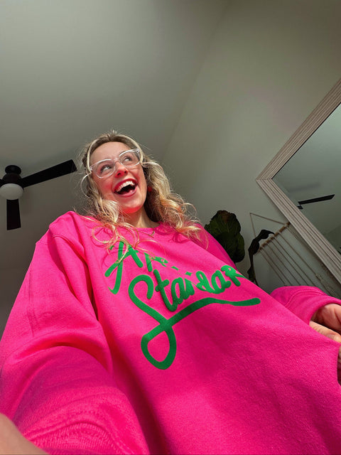 Lauren with Appalachian Standard merch on, smiling in the pink and green sweatshirt.