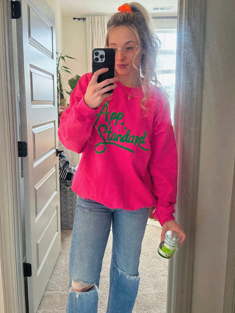 Lauren taking a mirror selfie wearing a pink and green Appalachian Standard sweatshirt.