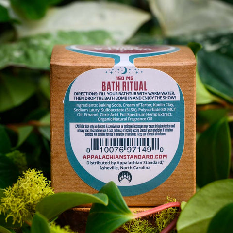 The back of the box of Appalachian Standard's Vanilla Chai CBD Bath Bomb surrounded by green plants