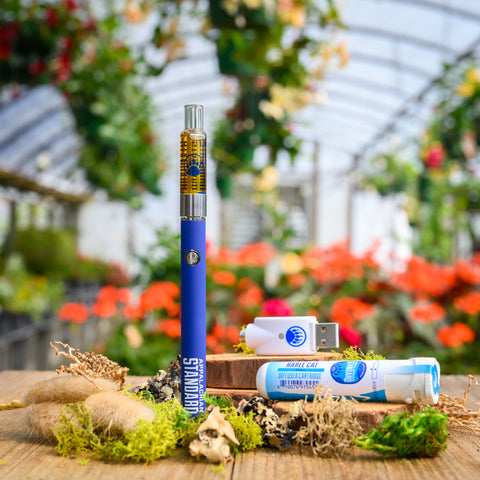 Harle Cat Vape Kit on wood table with moss and plant in background from Appalachian Standard