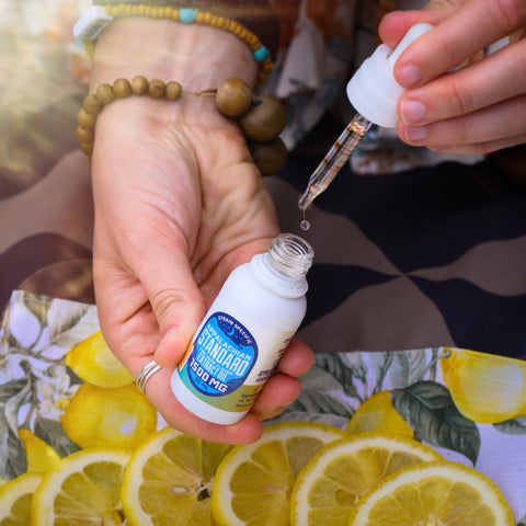 Lemon Cheesecake Hemp Oil tincture held in fiddyshadesofgreen's hand with bracelets on top of lemons by Appalachian Standard