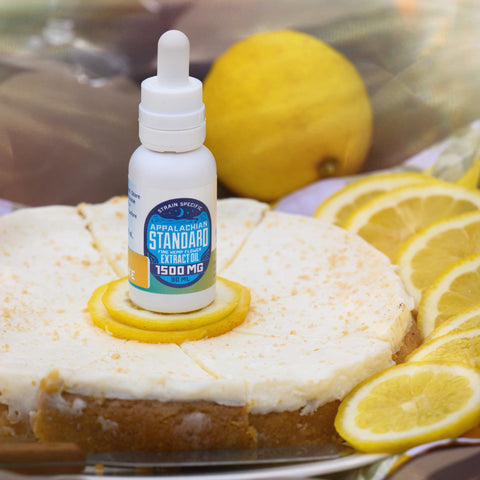 Hemp oil tincture bottle sitting on top of a lemon cheesecake.