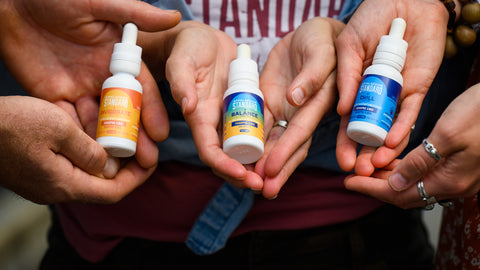 Three pairs of hands cupped holding 1 oz bottles of Appalachian Standard's tinctures from the CBD Tincture Trio