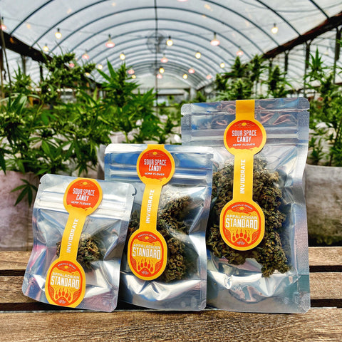 Award Winning Sour Space Candy hemp flower in three sizes on a wooden platter with plants in the background grown and packaged by Appalachian Standard
