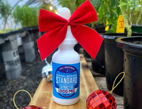 A 1 oz bottle of Appalachian Standard's tincture with a red bow wrapped around the top