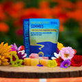 A bag of Appalachian Standard's All-Natural CBD Gummies and pieces of the CBD gummies on a wooden platter surrounded by flowers