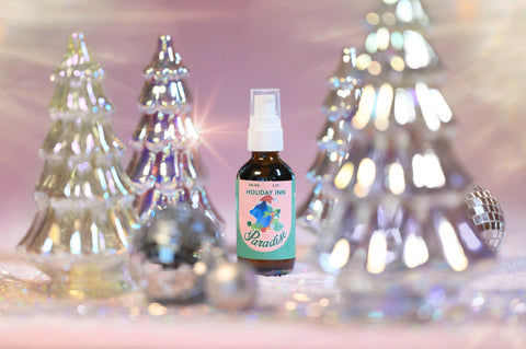 A photo of Appalachian Standards Limited Edition, Holiday Inn Paradise Body Oil surrounded by shiny glass decor christmas trees and disco balls.