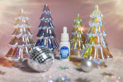 A photo of Appalachian Standards Limited Edition Peppermind Mocha CBD Tincture surrounded by sshiny Christmas trees, and disco balls.