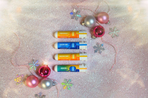 A photo of Appalachian Standards MistleToke CBD Rollie Bundle featuring their best-selling rollies Hawaiian Haze, Cherry Uno, Sour Space Candy, and Abacus. The rollies are surrounded by ornaments, snow flakes and snow.