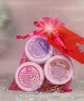 A photo of Appalachian Standards Holly Jolly Hydration Set, featuring their Limited Edition body creams, sandalwood vanilla, snow kiss, and Appalachian winter. The body creams are bundles in  pink mesh bag with a red Christmas tag.