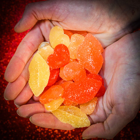 Two hands cupped together holding multiple Pucker Up Sour CBD Gummies