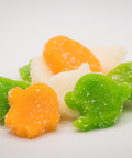 Colorful CBD Ghoulish Gummies shaped like ghosts and pumpkins on a white background.