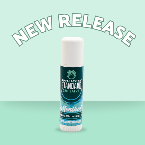 Appalachian Standard's CBD Hemp Menthol Salve Stick with a blue, mint green, and dark green label and mint green backdrop that says "New Release" on top.