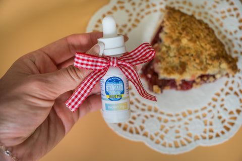 Appalachian Standard CBD Cherry Pie tincture being held in front of a Cherry Pie.