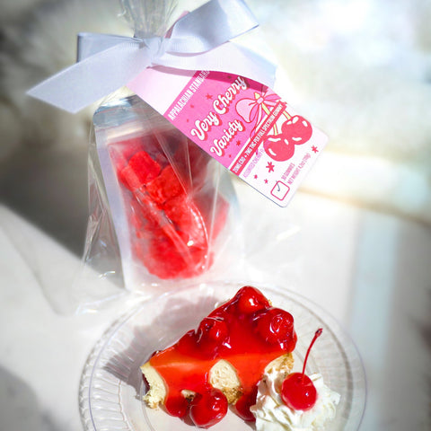 Miniature cake with cherry on top and packaging labeled 'Very Cherry' on a marble surface.