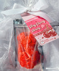 Red candy in a clear bag with a pink label on a white textured background