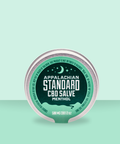 Appalachian Standard's Full Spectrum CBD Hemp Menthol Salve in a chrome tin with a mint green/dark green label on a mint green, ombre background.