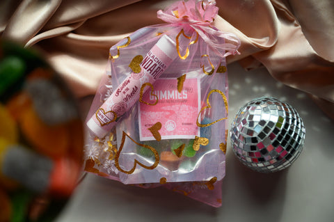 Appalachian Standard's Valentine's Special Offer Rollin' in the Sheets Bundle with Altitude Adjusting Hemp Gummies and Rollin' in the Sheets Blend in a pink bag with sparkly gold hearts and a disco ball and satin pillow case.