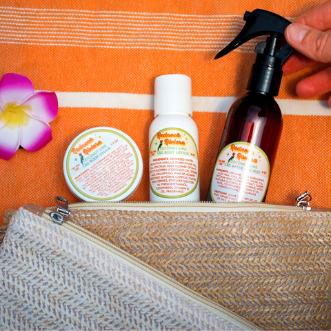 Appalachian Standard Coconut Lime Redneck Riviera CBD skincare set — body cream, body lotion, and after-sun mist — displayed in the open dark woven straw travel bag on an orange beach towel with a tropical flower