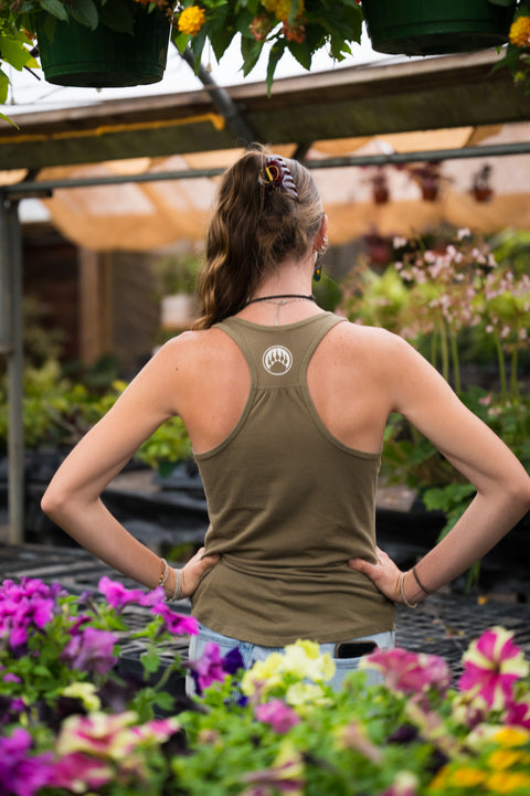 Person wearing a green tank top with a paw print design in a garden setting