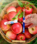 Apple-Achian apple-flavored vape in a hand held over a bushel of apples in a basket by Appalachian Standard. 