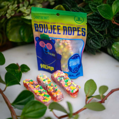 A bag and three pieces of Appalachian Standard's Boujee Ropes CBD Candy on a white platter with plants in the background