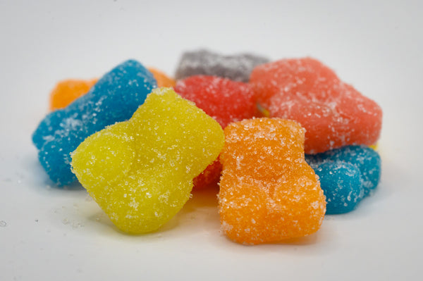A pile of yellow, orange, blue, red, orange, and purple gummies coated in sugar