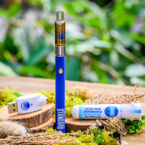 Appalachian Standard's Cherry Mom CBD Vape Kit on wood table surrounded by moss and plants