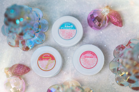 Balm jars with colorful labels on a glittery surface