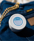 Appalachian Standard Dad Bod Cream, 1.5 oz jar, with 188mg CBD, styled on a pair of Wrangler jeans, next to a gold chain.