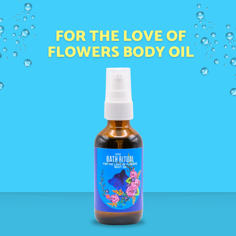 A bottle of Bath Ritual 'For the Love of Flowers' body oil centered on a bright blue background with yellow text and floating bubble graphics. The bottle is amber glass with a white spray top and a blue label decorated with pink flowers and a blue lotus.