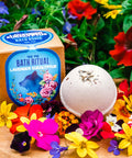 Appalachian Standard's Lavender Eucalyptus CBD Bath Bomb next to its box on a piece of wood surrounded by flowers