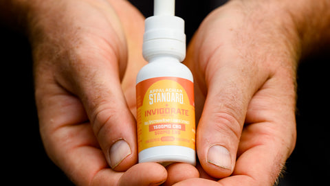 Cupped hands hold a 1 oz bottle of Appalachian Standard's Invigorate CBD Tincture