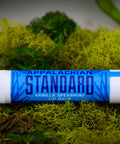 A stick of Appalachian Standard's Vanilla Spearmint Lip Balm on a bed of moss