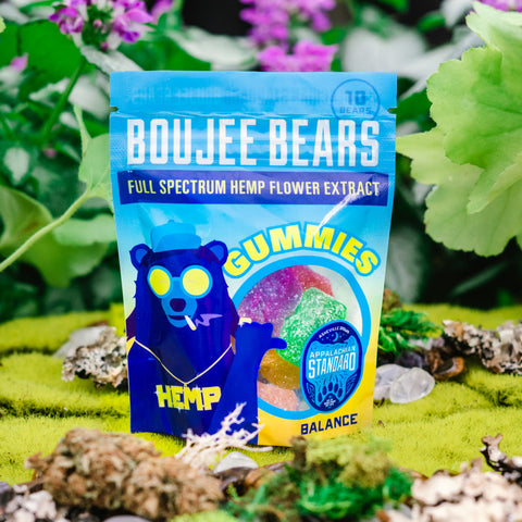 A bag of Appalachian Standard's Boujee Bears CBD Gummies on a bed of moss with plants and flowers in the background