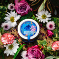 An overhead view of Appalachian Standard's tin of CBD Botanical Dream Bath Soak on a piece of wood surrounded by flowers and plants