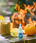 A bottle of Appalachian Standard's Orange Chai Hemp Oil Tincture on a wooden table with a mason jar of Orange Chai Latte and orange slices behind it. 