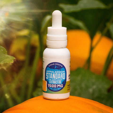 Appalachian Standard's Pumpkin Spice Latte CBD Tincture, sitting on top of a pumpkin, with a pumpkin patch in the background.