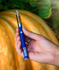 Appalachian Standard's Pumpkin Latte Vape, being held by a hand with a large orange pumpkin in the background.