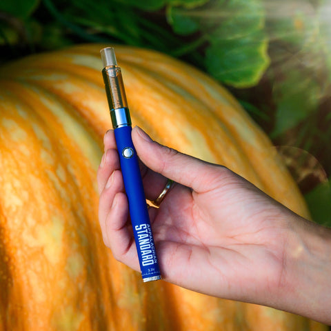 Appalachian Standard's Pumpkin Latte Vape, being held by a hand with a large orange pumpkin in the background.