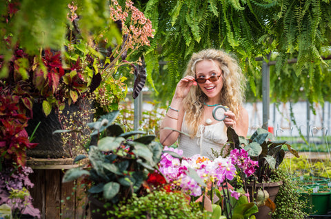 Woman in a garden setting surrounded by plants and flowers