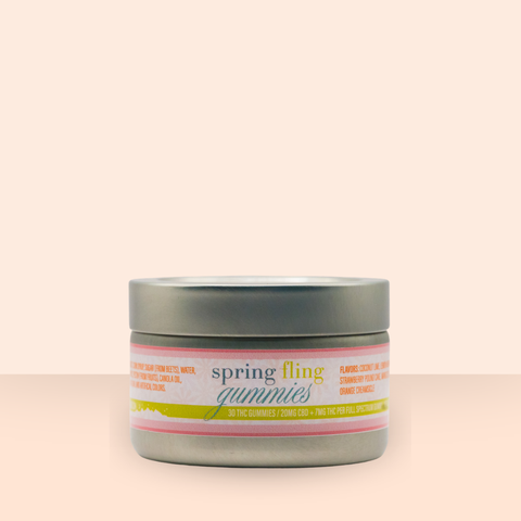 Appalachian Standard Spring Fling Gummies tin, closed, displayed on a soft peach background. The label reads "spring fling gummies — 30 gummies per tin" in cheerful multicolor typography with a pink and yellow stripe design.