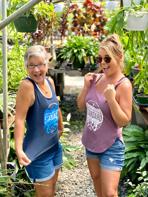 Two women standing in a garden center, surrounded by plants and gardening supplies.