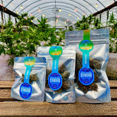 T1 hemp flower in three sizes on a wooden platter with plants in the background grown and packaged by Appalachian Standard