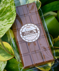 Appalachian Standard's Salted Croissant THC Chocolate bar in cellophane wrapping surrounded by plant leafs.