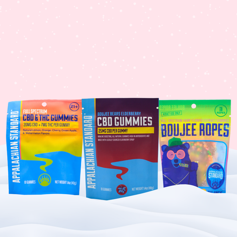 Three packages of CBD gummies and ropes on a white surface with a pink polka dot background