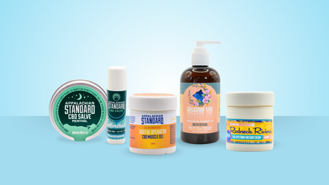 Collection of CBD products including salves and oils on a light blue background