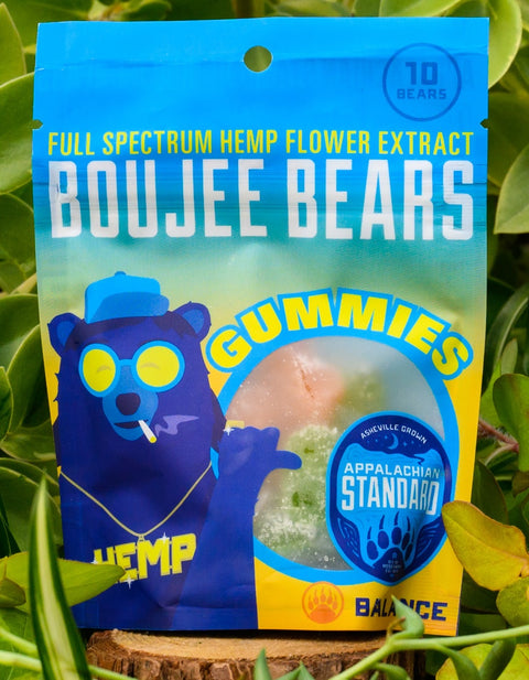 A bag of Appalachian Standard's Boujee Bear CBD Gummies on a wood slice surrounded by plants