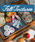 Picnic basket with apples, tinctures, and a cake on a checkered blanket with 'Fall Tinctures' text.
